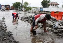 Terlihat Seseorang Memperbaiki Jalan yang Terkena Rob Banjir (Jateng Memanggil/Antara)